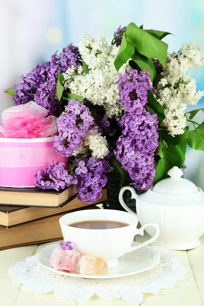 Samenstelling met prachtige lila bloemen, thee service op houten tafel op lichte achtergrond — Stockfoto