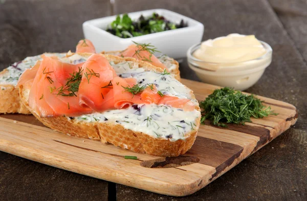 Sandwiches de pescado sobre tabla de cortar sobre mesa de madera — Foto de Stock