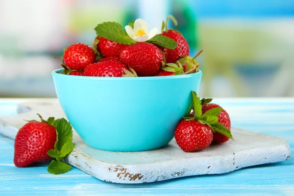 Ripe sweet strawberries in bowl on blue wooden table — Stock Photo, Image