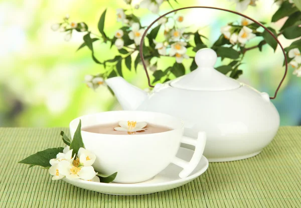 ถ้วยชากับมะลิ บนพรมไผ่ บนพื้นหลังที่สดใส — ภาพถ่ายสต็อก