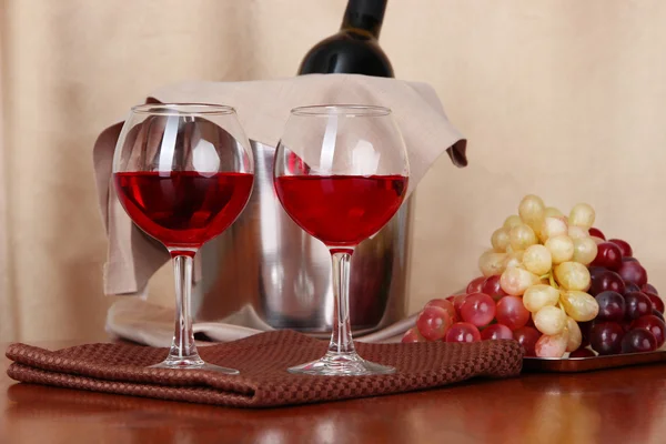 Vitigno e bicchieri su tavola rotonda su sfondo stoffa — Foto Stock