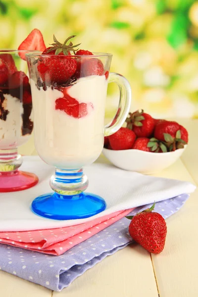 Deliziosi dessert alla fragola in vaso di vetro su tavolo di legno su sfondo naturale — Foto Stock