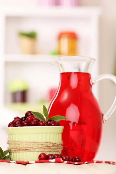 Pitcher of cranberry juice and red cranberries on table — Stock Photo, Image