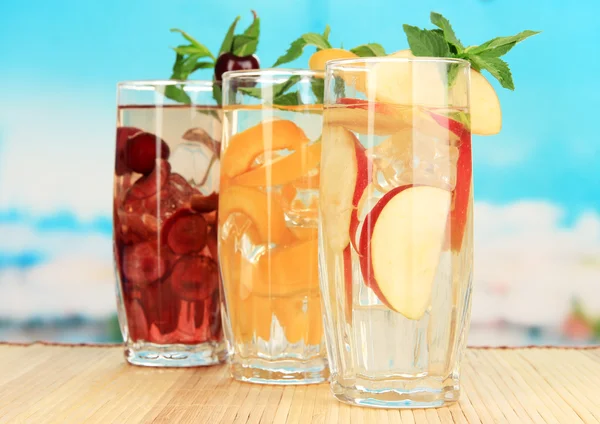 Vasos de bebidas de frutas con hielo sobre fondo azul — Foto de Stock
