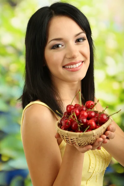 Flicka med färska körsbär på naturliga bakgrund — Stockfoto