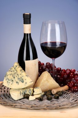 şarap, peynir ve üzüm hasır tepsi üzerinde ahşap masa mavi zemin üzerine siyah zemin natürmort