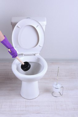 kadın bir klozet banyo unclog için bir dalgıç kullanır