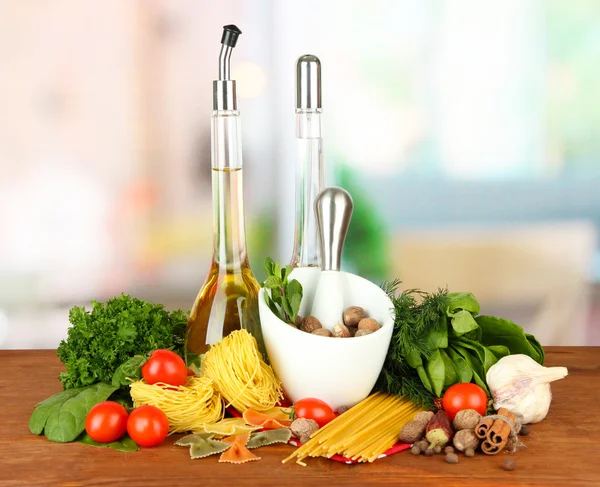 Composition of mortar, pasta and green herbals, on bright background — Stock Photo, Image