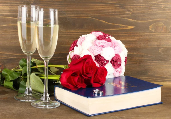 Anneaux de mariage sur bible avec des roses et des verres de champagne sur fond en bois — Photo