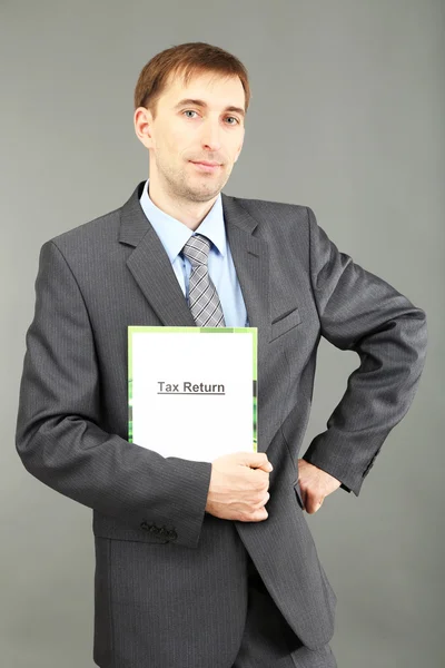 Young businessman with folder on grey backgroun — Stock Photo, Image