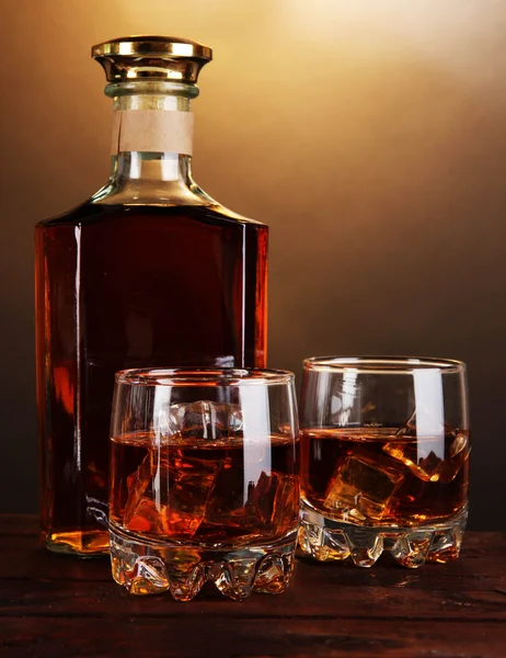 Brandy with ice on wooden table on brown background — Stock Photo, Image