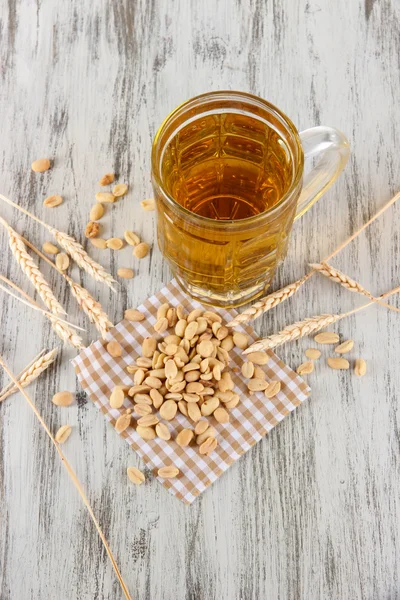 Bier in glas en noten op servet op houten tafel — Stockfoto