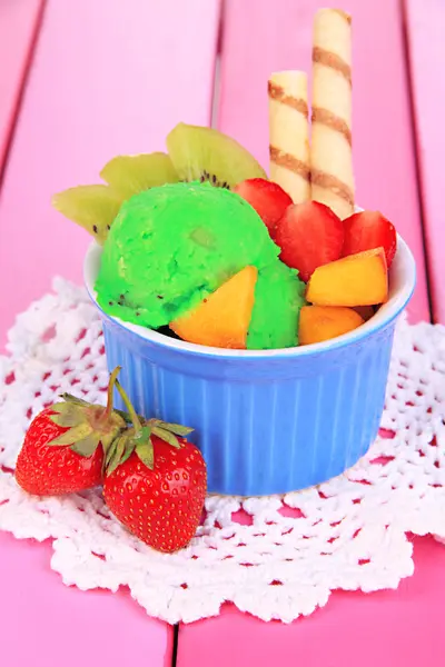 Delicioso helado con frutas y bayas en un tazón sobre una mesa de madera —  Fotos de Stock