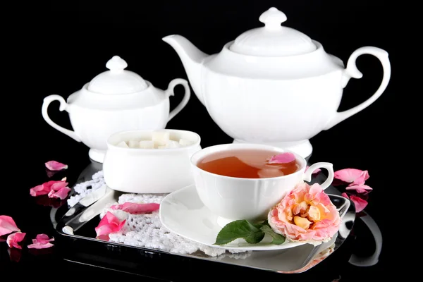 Kettle and cup of tea from tea rose on metallic tray on napkin black background — Stock Photo, Image