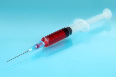 mavi zemin üzerine kan dolu plastik tek kullanımlık şırınga