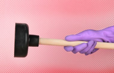 Toilet plunger in hand on pink background clipart