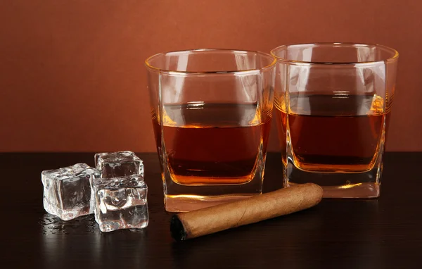 Glasses of whiskey and cigar on brown background — Stock Photo, Image