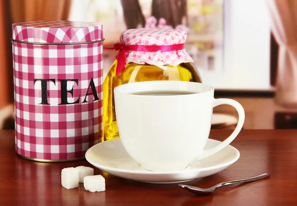 Jar and cup of tea on table in room — Stock Photo, Image