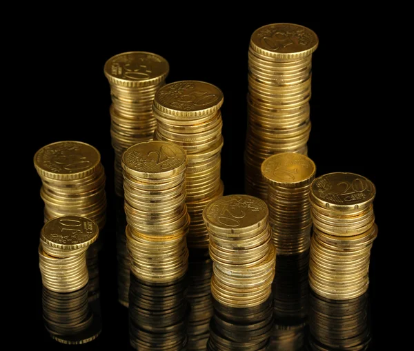 Many coins in columns isolated on black — Stock Photo, Image