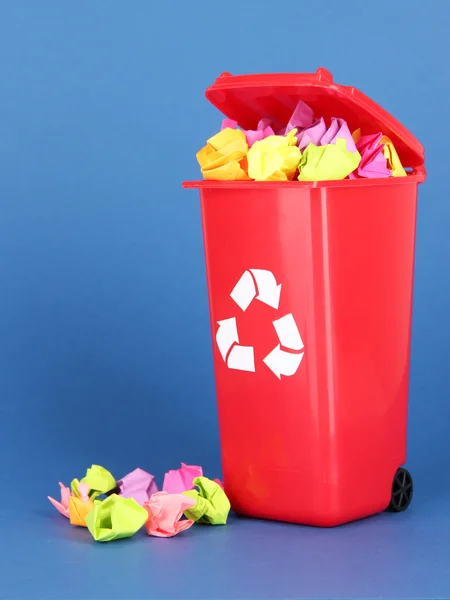 Recycling-Tonne mit Papieren auf blauem Hintergrund — Stockfoto