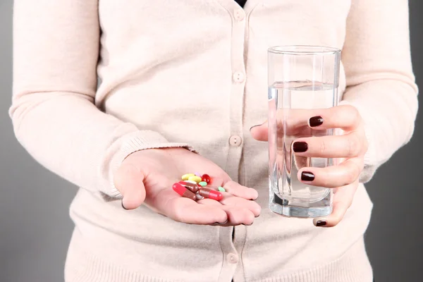 Vele pillen en glas water in de hand — Stockfoto