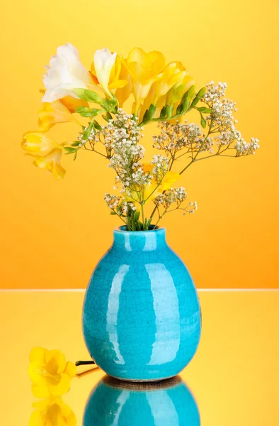 Belo buquê de freesia em vaso no fundo laranja — Fotografia de Stock