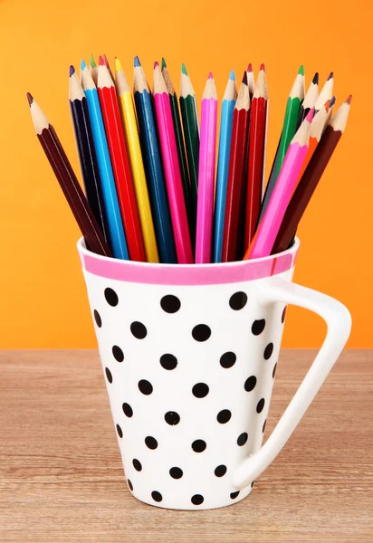 Colorful pencils in cup on table on orange background — Stock Photo, Image