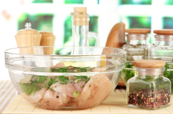 Hühnerfleisch in Glasschüssel, Kräuter und Gewürze auf dem Tisch im Fensterhintergrund — Stockfoto