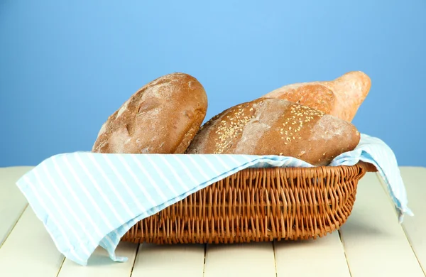 Composition with bread and sackcloth on wooden table, on color background — Stock Photo, Image