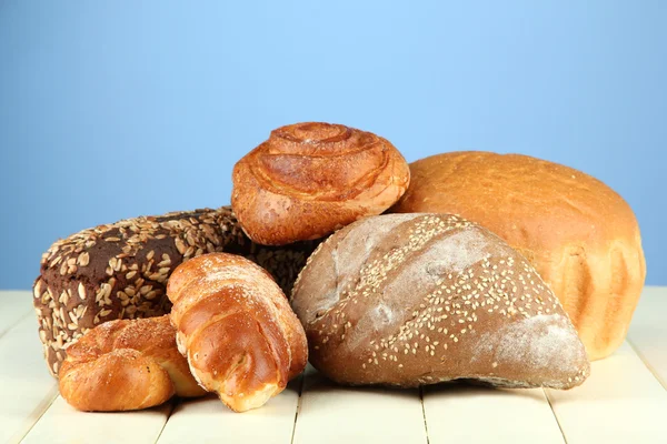 Composition with bread and rolls on wooden table, on color background — Stock Photo, Image