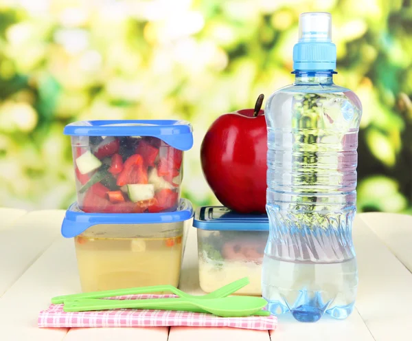 Tasty lunch in plastic containers, on wooden table on bright background — Stock Photo, Image