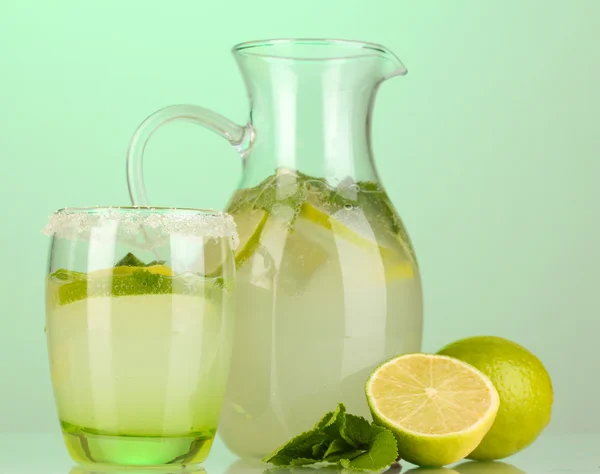 Limonade in werper en glas op turkooizen achtergrond — Stockfoto