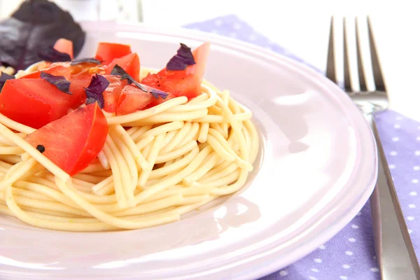 Spaghetti con pomodori e foglie di basilico su tovagliolo su fondo di legno — Foto Stock