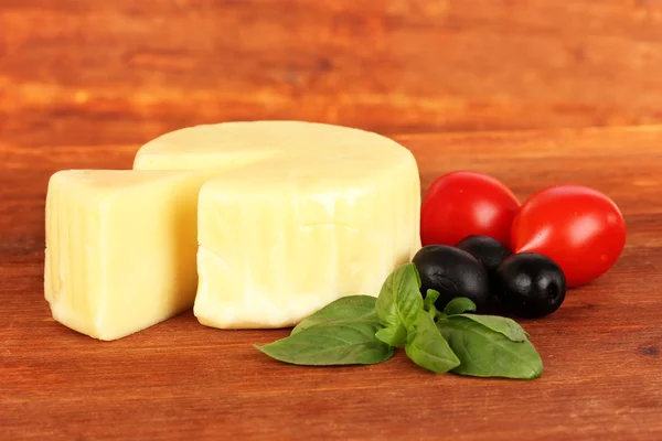 Käse-Mozzarella, Basilikum und Gemüse auf Holzgrund — Stockfoto