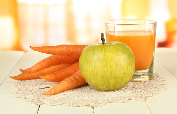 Un mucchio di carote e mela verde, vetro di succo, su tavolo di legno a colori su sfondo brillante — Foto Stock