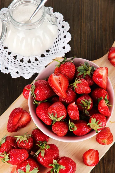 Strawberries in bowl on board cutting on wooden table — Stock Photo, Image