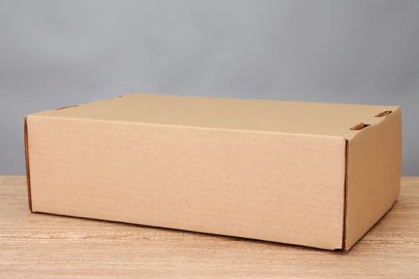 Paketkasten auf Holztisch, auf grauem Hintergrund — Stockfoto