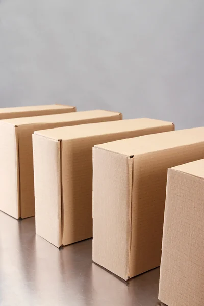 Cardboard boxes on conveyor belt, on grey background — Stock Photo, Image