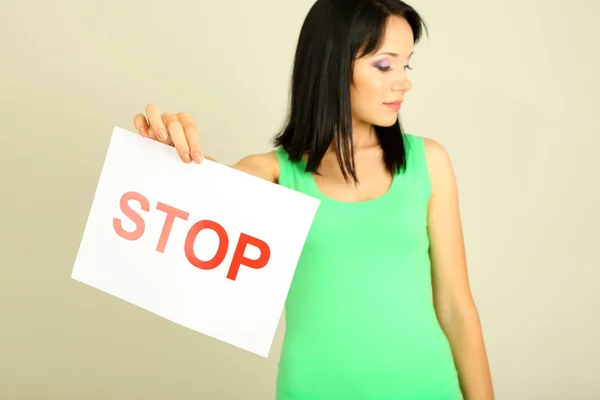 Mädchen zeigt Stoppschild auf grauem Hintergrund — Stockfoto