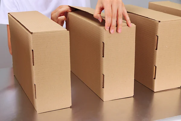 Worker working with boxes at conveyor belt, on grey background — Stock Photo, Image