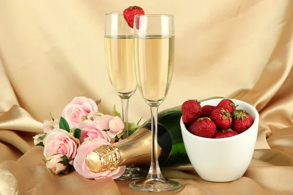 Romantic still life with champagne, strawberry and pink roses, on color fabric background — Stock fotografie