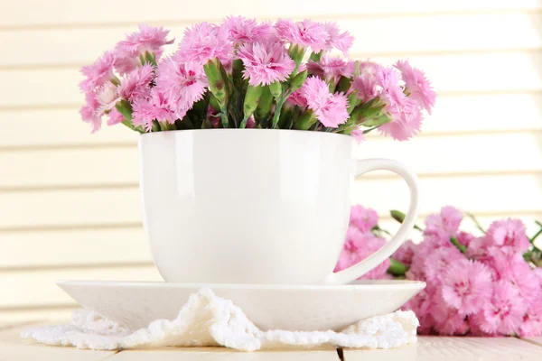 Muchos pequeños dientes de color rosa en taza sobre fondo de madera — Foto de Stock