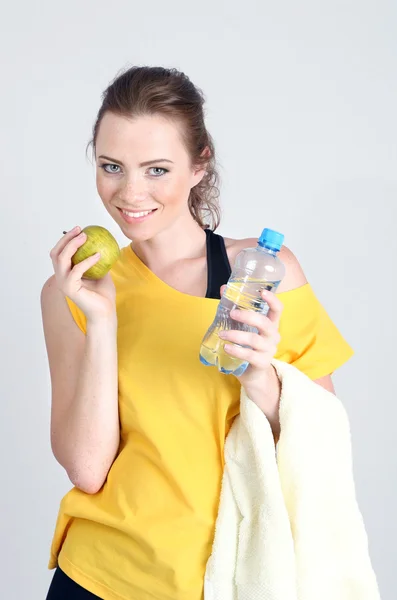 Beautiful young woman with bottle of water and apple — Stock Photo, Image