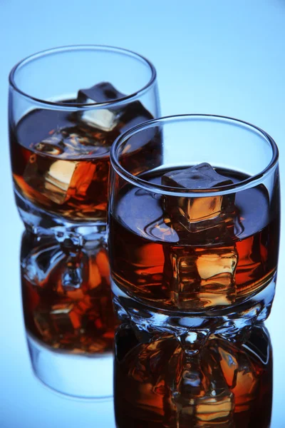 Brandy glasses with ice on blue background — Stock Photo, Image