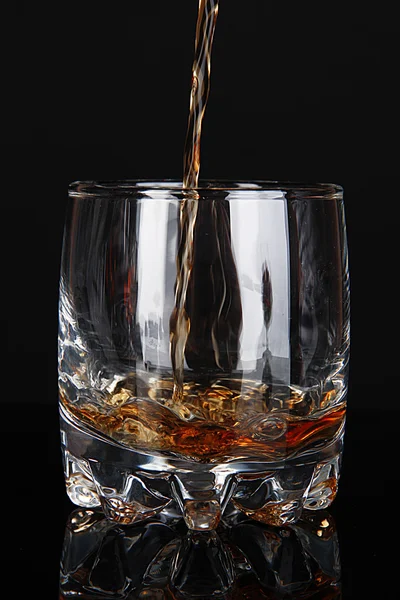 Brandy verser dans le verre sur fond noir — Photo