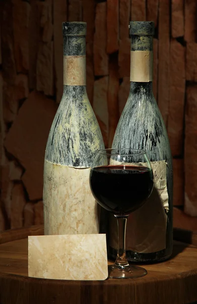 Composition avec vieille bouteille de vin et verre à vin dans une ancienne cave, sur fond sombre — Photo