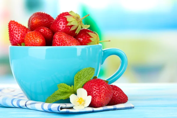 Zralé sladké jahody v poháru na modré dřevěný stůl — Stock fotografie