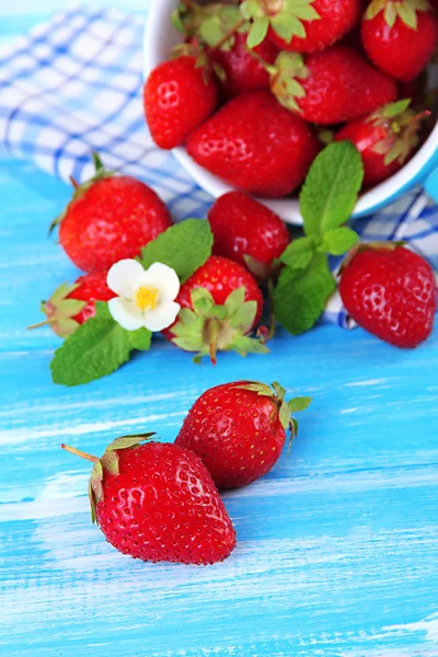 Fresas dulces maduras en taza sobre mesa de madera azul —  Fotos de Stock