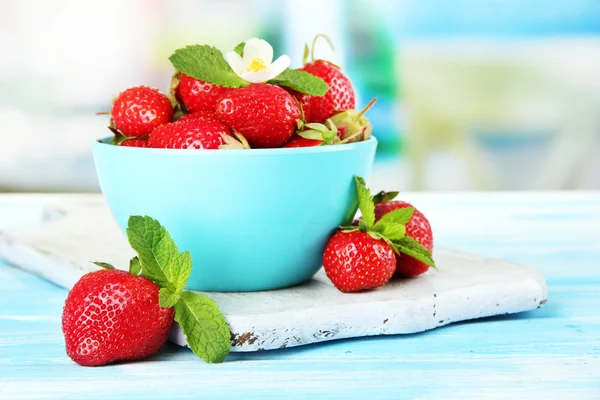 Zralé sladké jahody v misce na modré dřevěný stůl — Stock fotografie