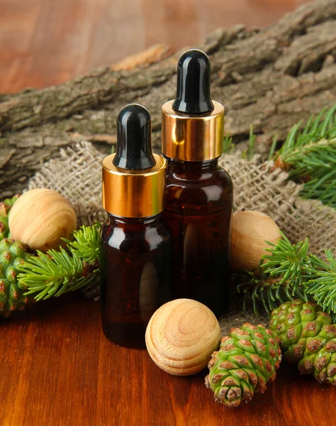 Bottles of fir tree oil and green cones on wooden table — Stock Photo, Image